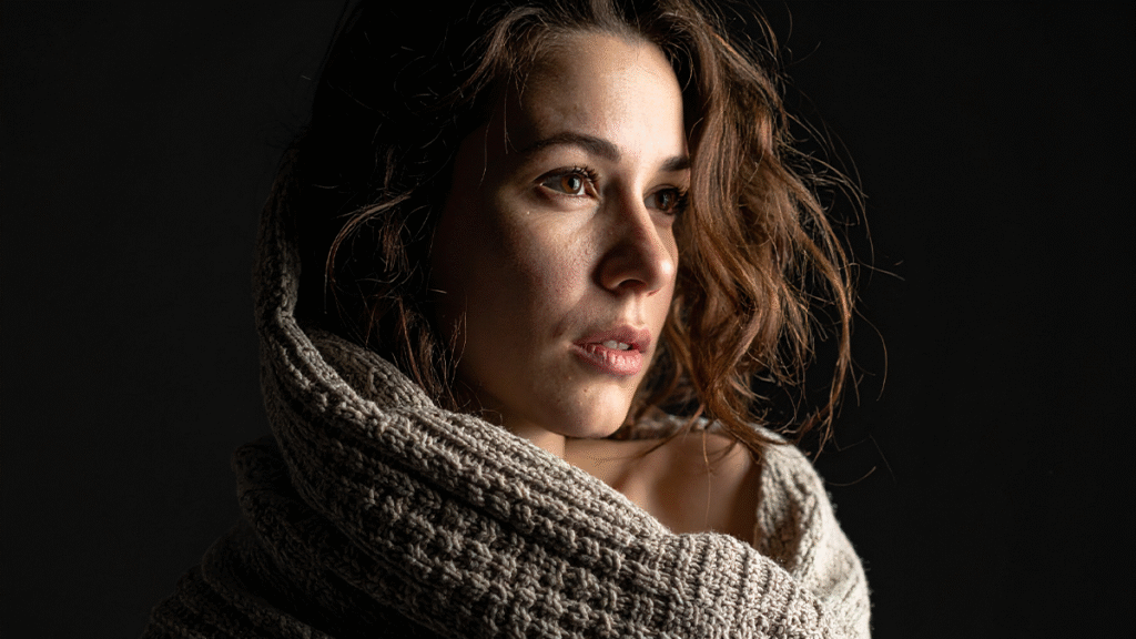 Bağımlılık tedavisi karaı alan Karanlıkta kendine sarılan ve umutla bakan genç kadın görseli.